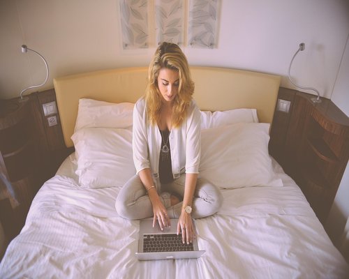 Person working on a laptop near a bright window at home