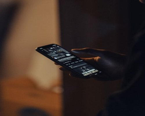 A person scrolling a smartphone in a dimly lit room